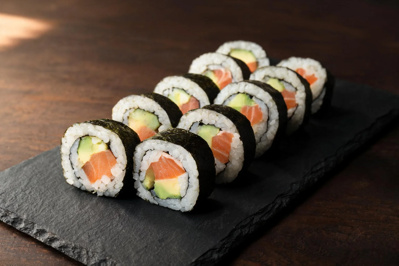 Makis saumon avocat sur une ardoise noire (image d'illustration).