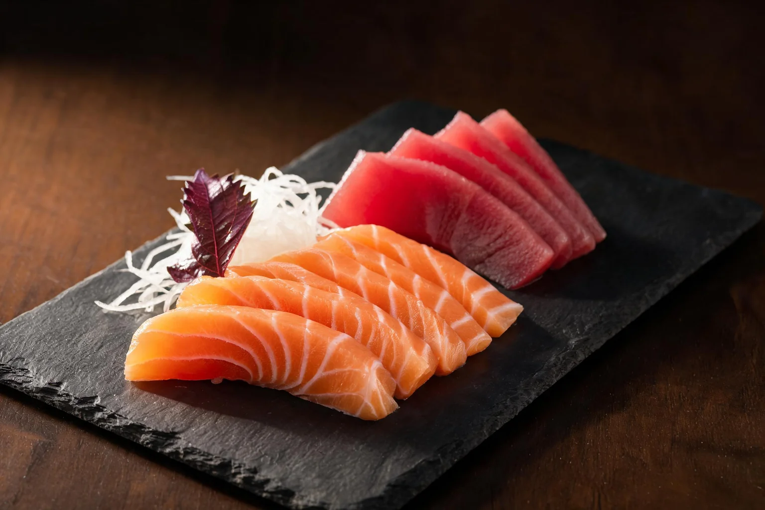 Tranches de saumon et de thon, radis râpé et feuille de shiso sur une ardoise (image d'illustration).