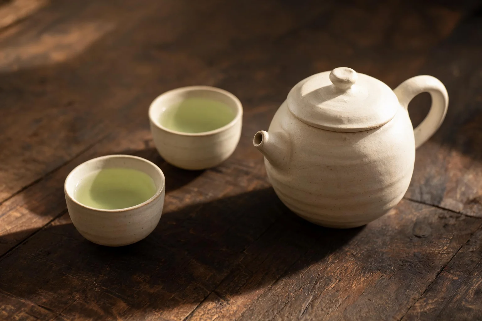 Une théière en céramique et deux petites tasses de thé vert. (image d'illustration)